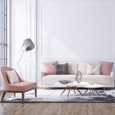 Salón con una gran pared blanca y un ventanal, con un sofá con cojines y un sillón como ejemplo del máster general en interiorismo y decoracion de INNADI, Madrid